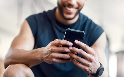 Smiling man in gym clothing starting a health intake on his phone
