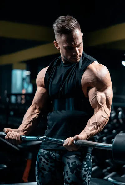 Muscular man doing barbell curls in gym